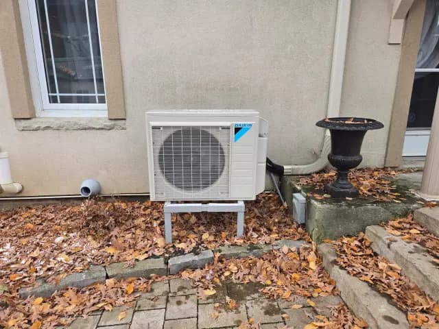 Outdoor heat pump unit with Daikin logo installed near house