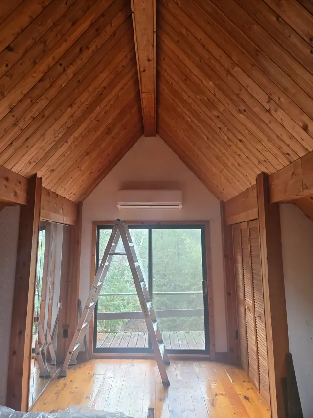 Air conditioning unit installed in a wooden room with a ladder leaning against the wall