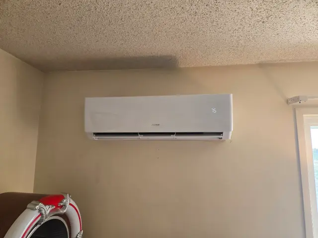 Air conditioning unit mounted on a wall with a digital display showing temperature