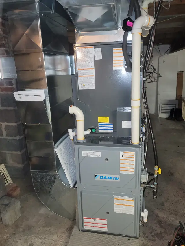 A Daikin furnace is installed in a basement with various components like the air filter, control panel, and