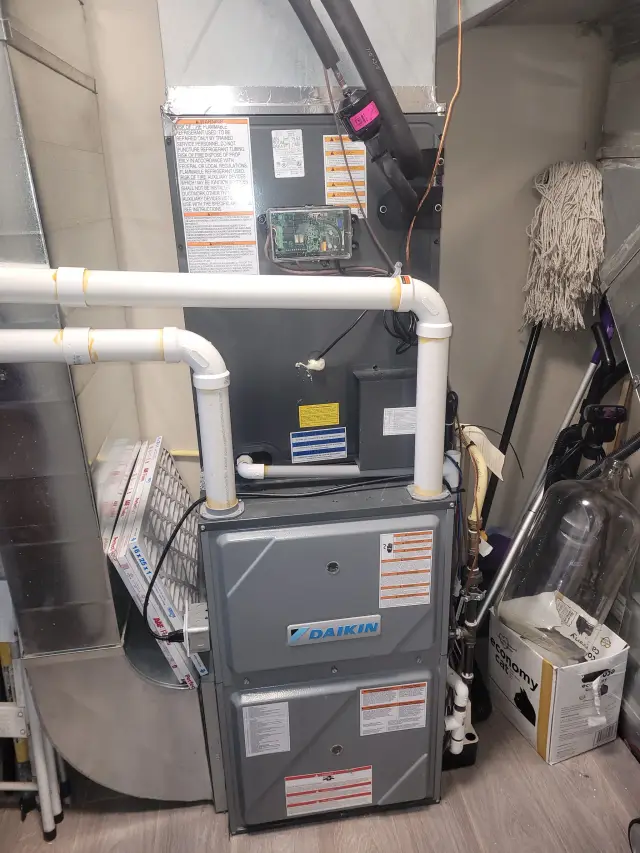 A Daikin furnace is installed in a utility closet with various tools and equipment around it