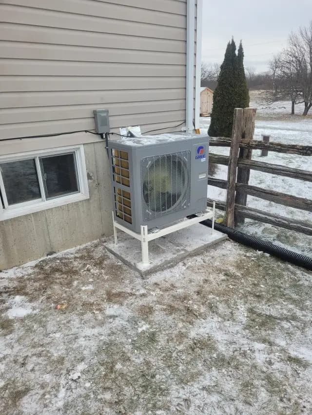 A newly installed outdoor Gree heat pump with a large fan and a gray casing is placed on