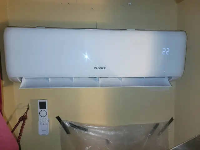A white, wall-mounted air conditioning unit with a digital display showing temperature. The brand 'Gree' is visible on