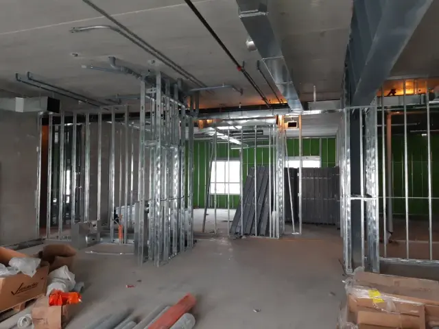 Metal studs and drywall framing with various construction materials scattered around