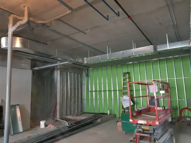 Metal HVAC ducts are installed on the ceiling, with visible insulation and wiring. The ducts are silver and