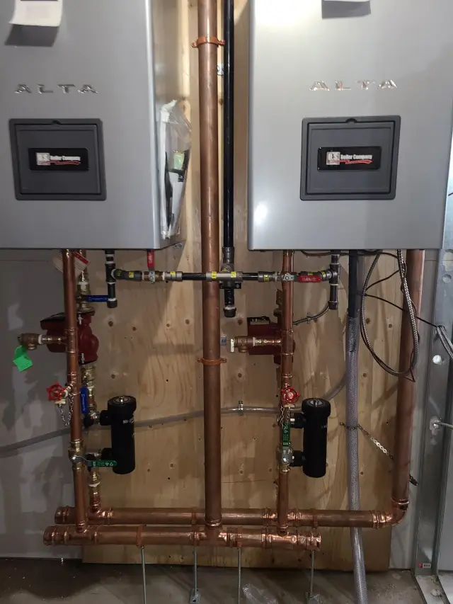 A close-up view of an Alta water heater, showcasing its digital display and the intricate network of pipes