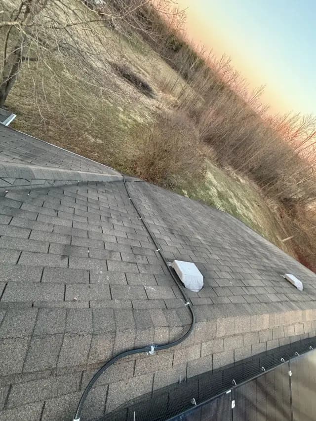 Solar panels are installed on the roof of a house, with a view of the surrounding landscape