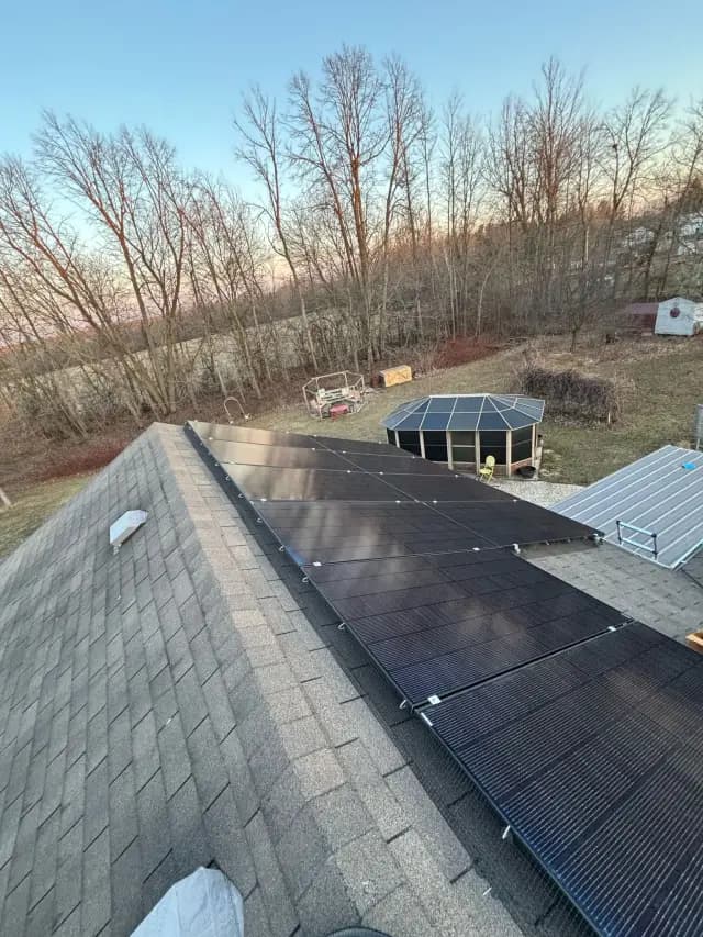 Solar panels on roof with shingles and trees in background