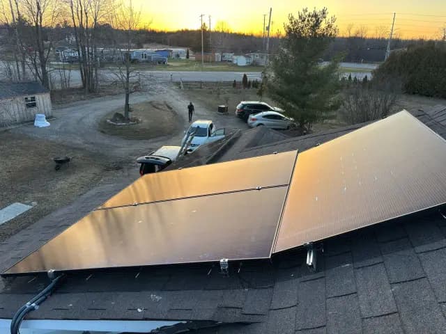 Solar panels on a house roof during sunset with a clear view of the setting sun in the