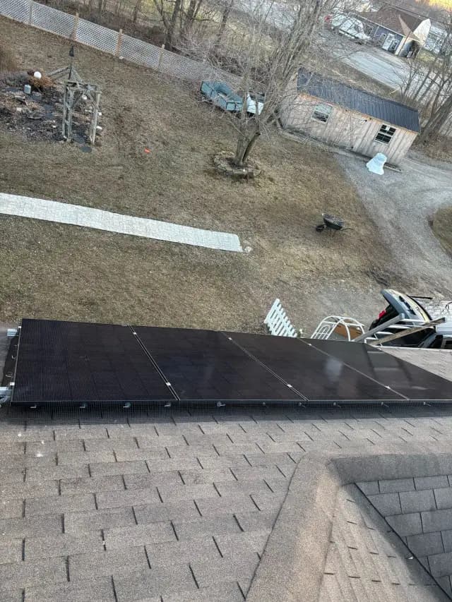 Solar panels on a roof, with a view of a yard and a vehicle