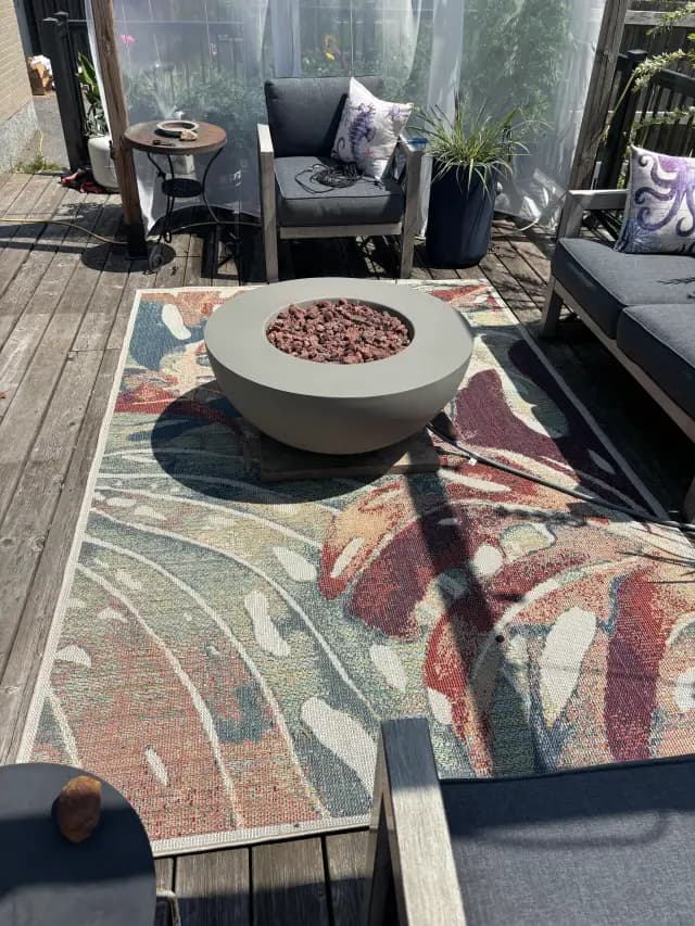A circular propane fire pit with a gray finish is the centerpiece of this outdoor patio setting. It's
