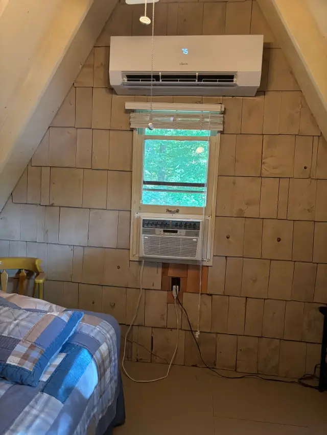 Air conditioner unit with digital display and remote control, placed above a window that offers a view of