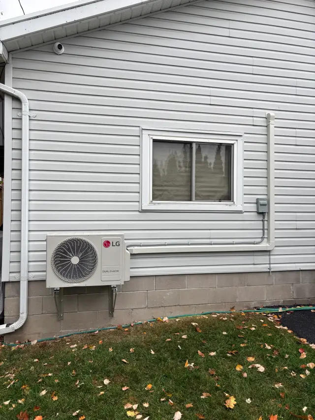 A newly installed outdoor Gree heat pump with a large fan and a white casing is mounted on