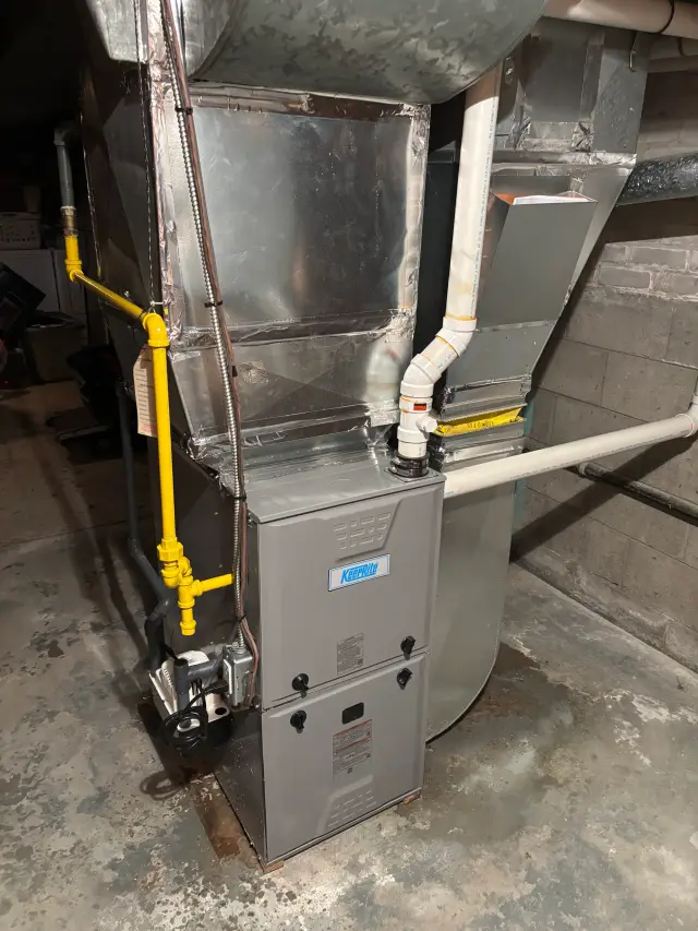 Outdoor Gree heat pump with a silver metallic casing, yellow piping, and a white vent. The pump is