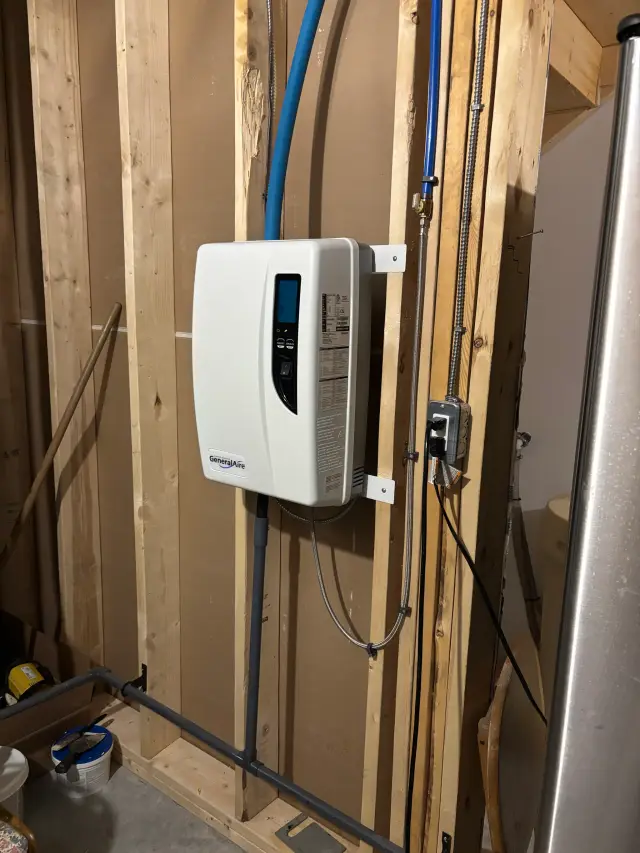 Water heater with digital display and blue piping installed on wooden studs