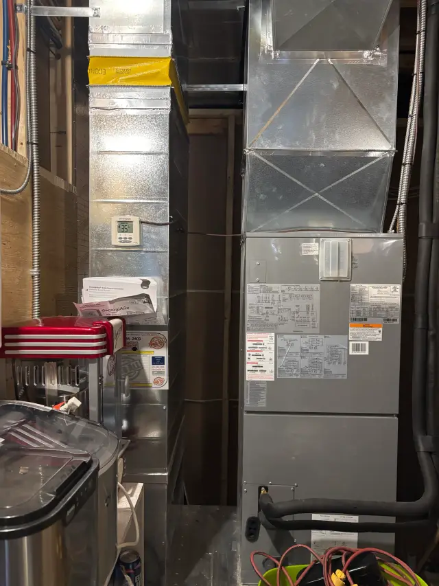 A silver HVAC unit with a digital display is mounted on a wall, showing a temperature of 75°F.