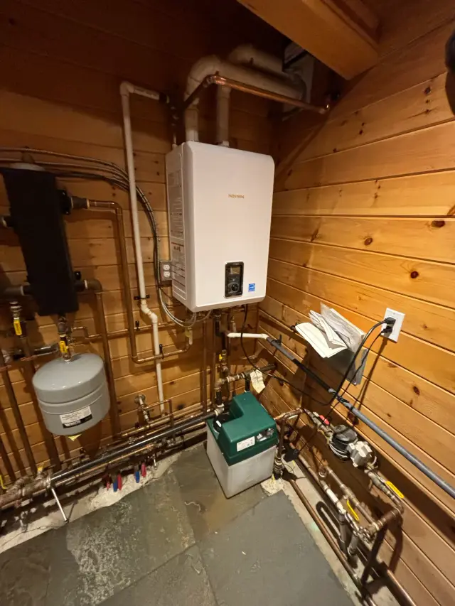 Tankless water heater with digital display and piping system mounted on wooden wall