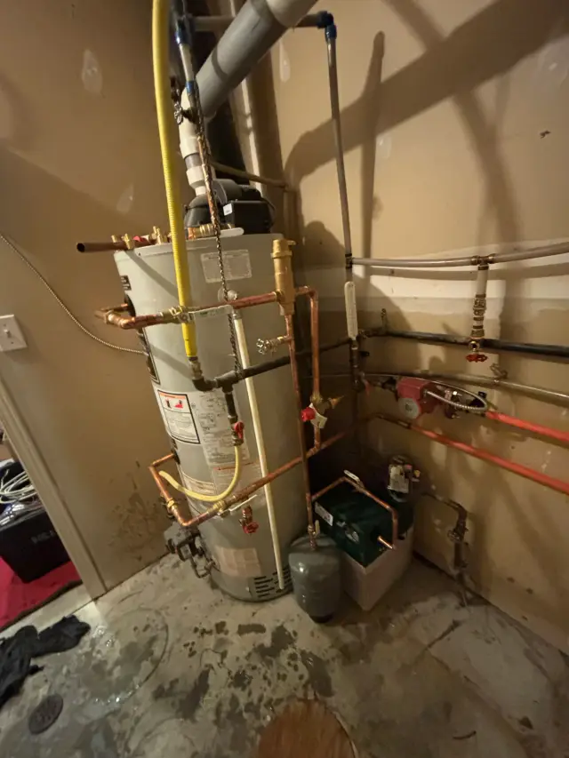 A water heater with various pipes and fittings, including a yellow gas line and a black exhaust vent