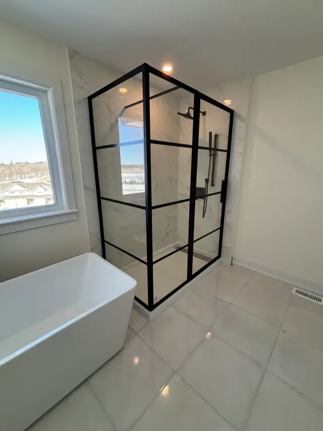 A white freestanding bathtub with a minimalist design is showcased in a bathroom with large tiles. The tub