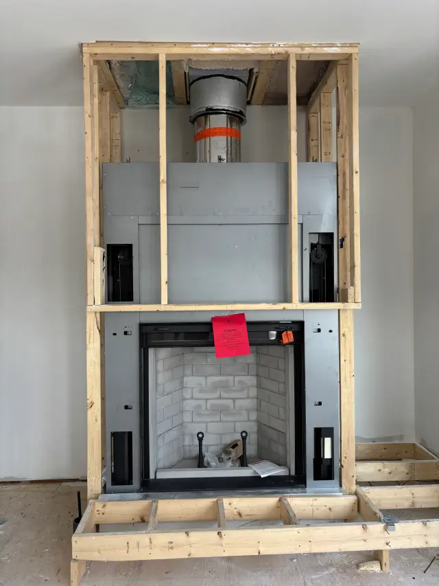 Wooden framework with metal fireplace insert and chimney, with a red notice attached