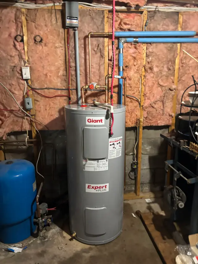 A Giant water heater is installed in a basement with insulation and various equipment around it