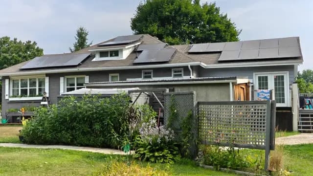 Solar panels on roof of a house with a garden in the foreground