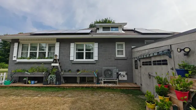 An outdoor Gree heat pump is installed on a wooden platform. The unit is gray and has a