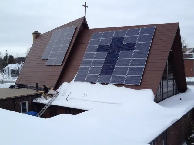 Solar panels on roof of residential building with snow around