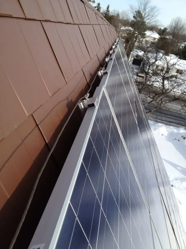 Solar panels on roof with metal brackets and cables attached
